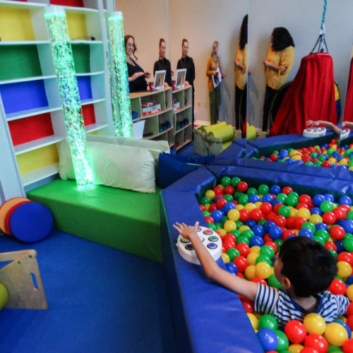 young boy plays in ball pit inside sensory room