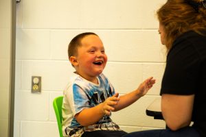 A child laughing with an ABA therapist.