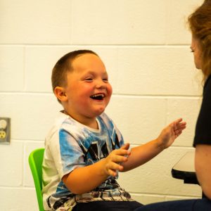 A child laughing with an ABA therapist.